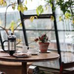 round brown wooden table with french press on top with white ceramic teacup beside