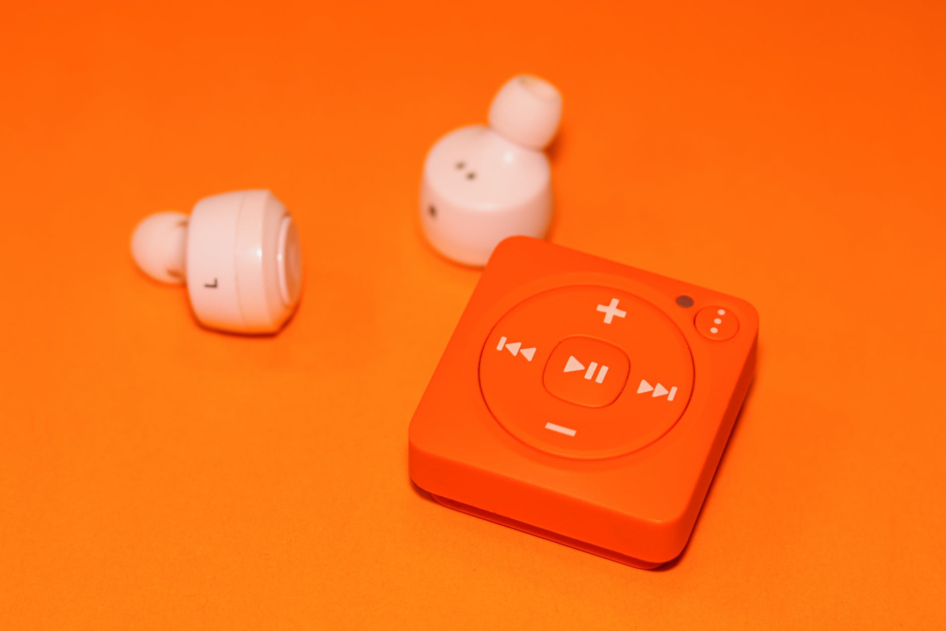 white earphones beside orange music player