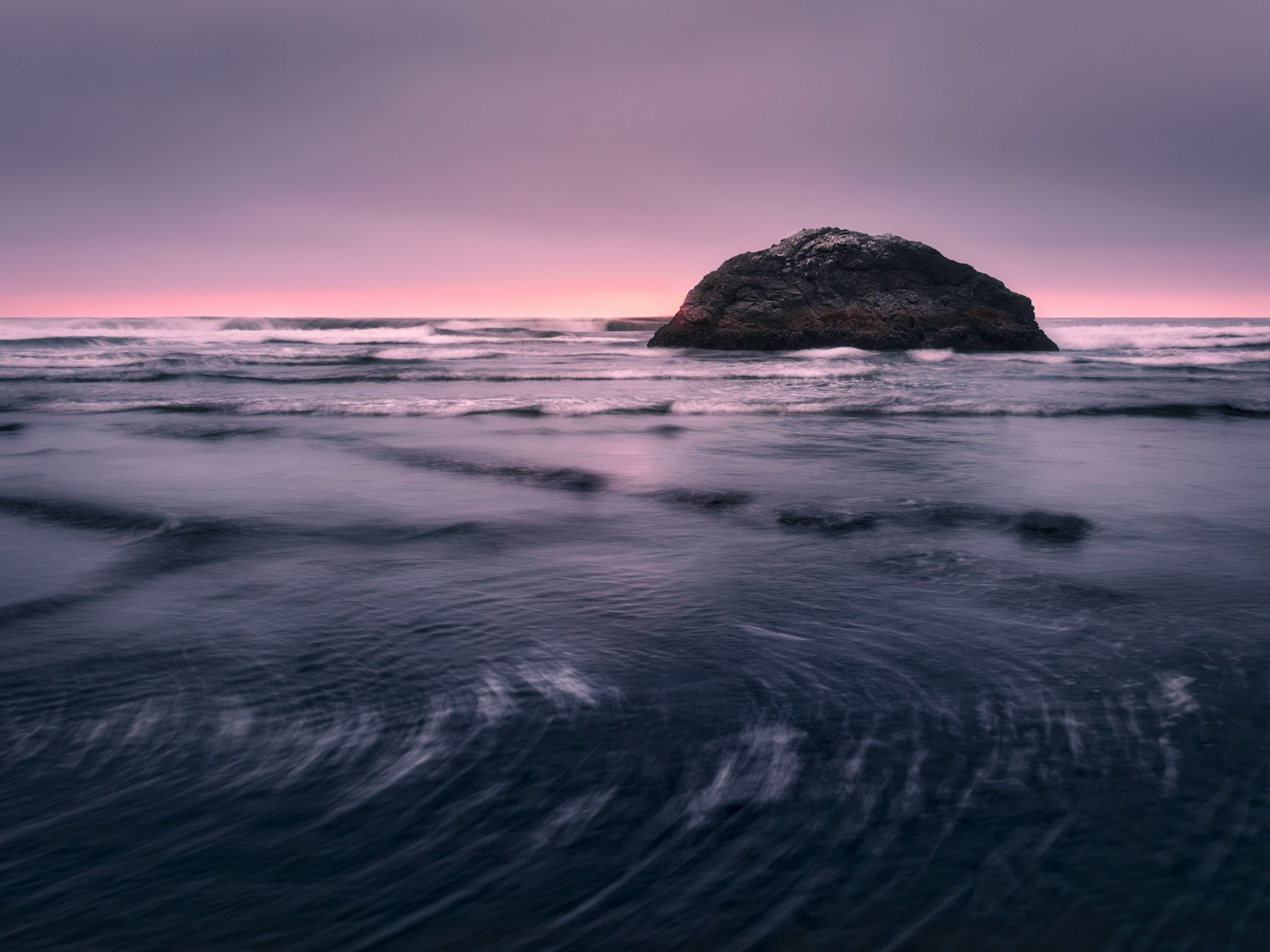 A rock in the middle of a body of water